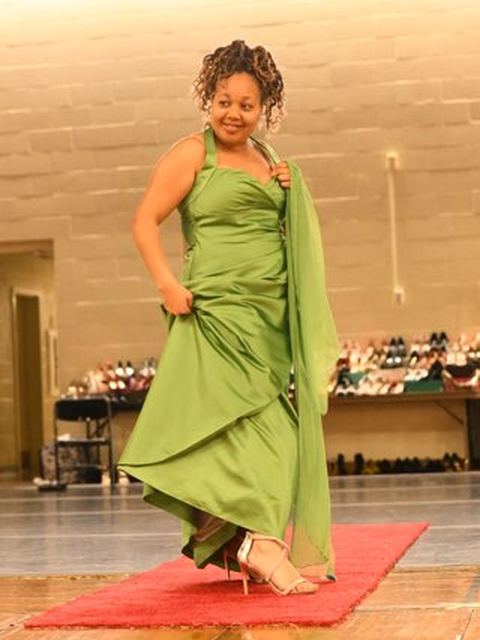 A student on the red carpet in a green gown at the Prom Boutique
